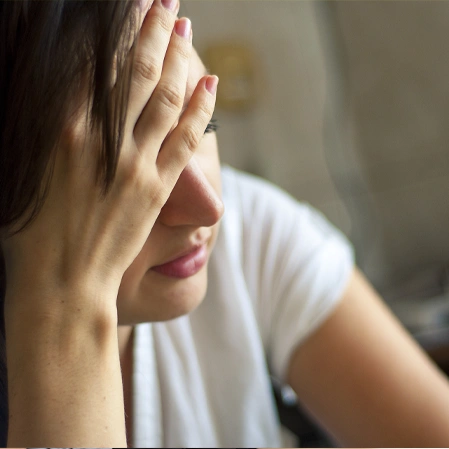 Person Resting Forehead On Hand While Experiencing Head Discomfort
